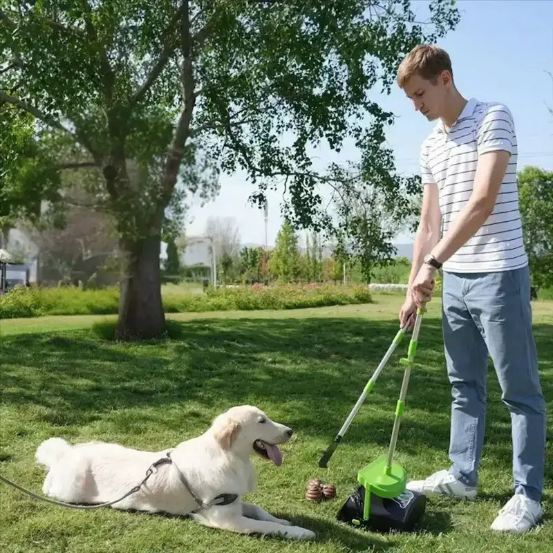 Un homme ramasse les crottes de son labrador dans un parc avec la pelle à crottes pour chien.