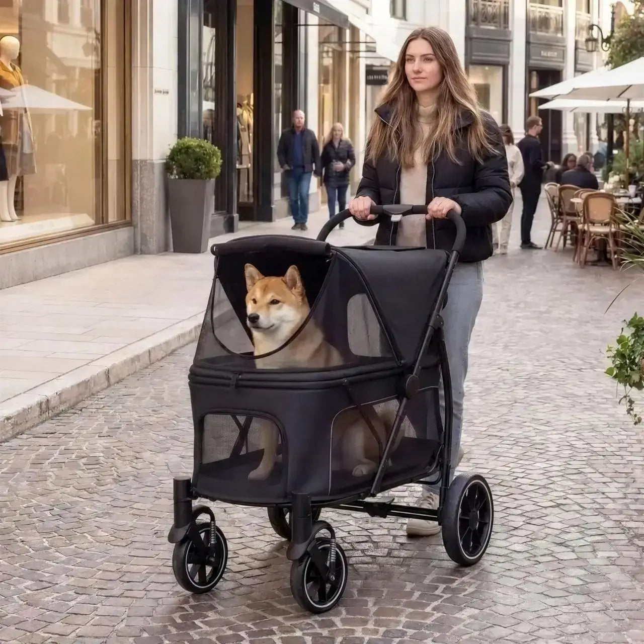 Une femme se promène en ville avec son shiba inu dans la poussette pour gros chien noire.