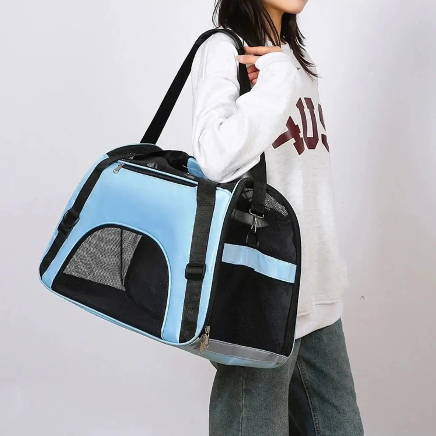 Une femme porte le sac de transport pour chien bleu en bandoulière.