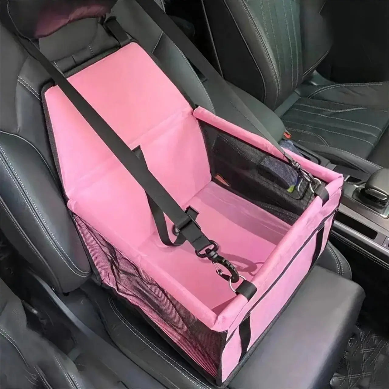 Un siège pour chien de voiture sur le siège avant de couleur rose.