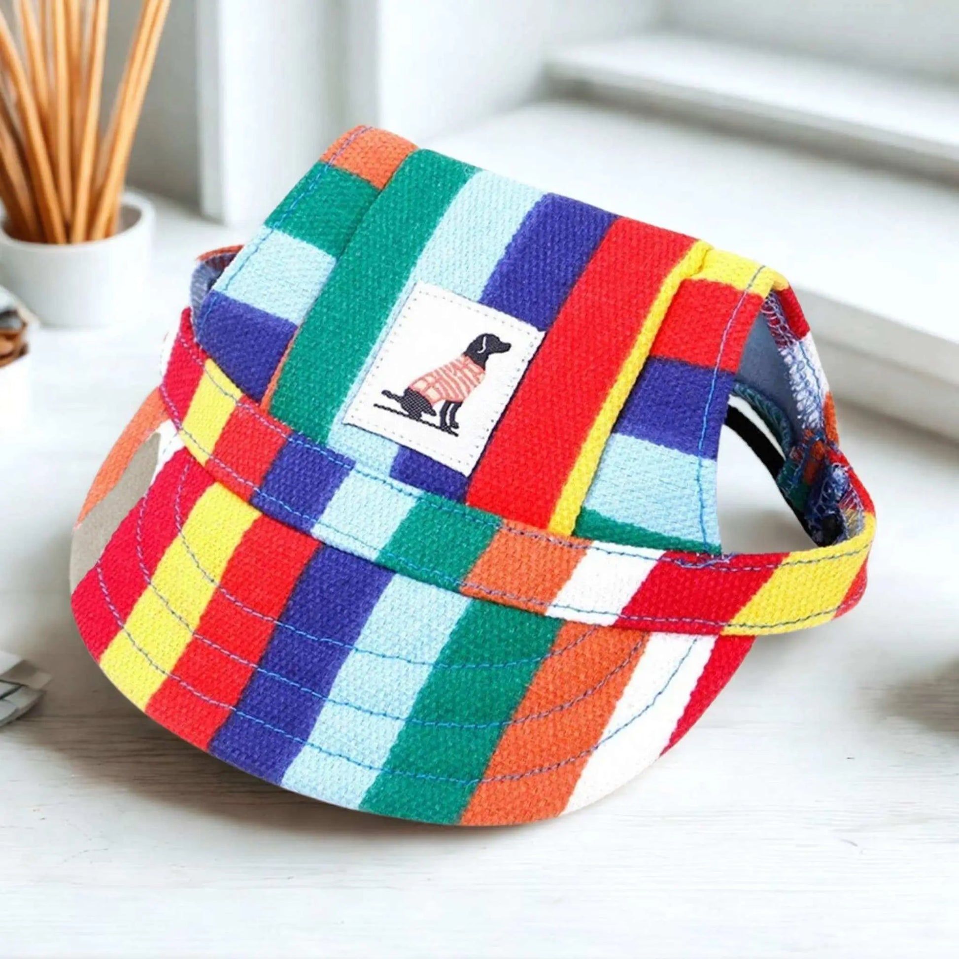 Une casquette chien à rayures multicolores sur un bureau blanc.