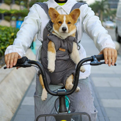Sur un trottoir, un homme à vélo porte un chien sac de transport avant avec un corgi à l'intérieur.