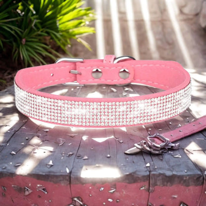 Un collier rose pâle avec strass sur une planche avec des rayons de soleil qui se reflètent dessus.