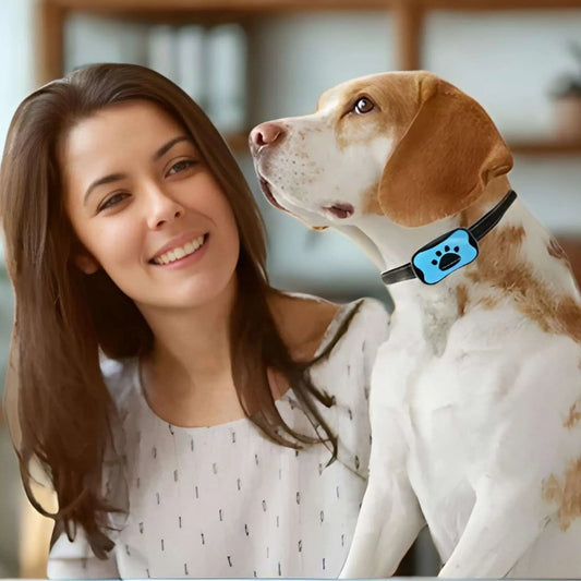 Une femme souriante regarde son beagle avec son collier anti-aboiement bleu.
