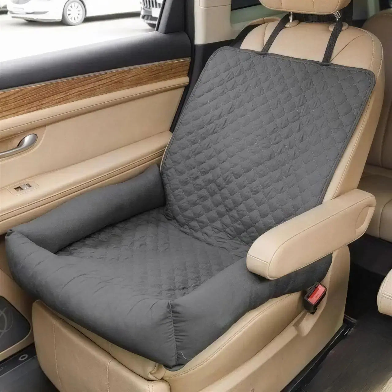 Un coussin pour chien de voiture gris sur le siège avant.