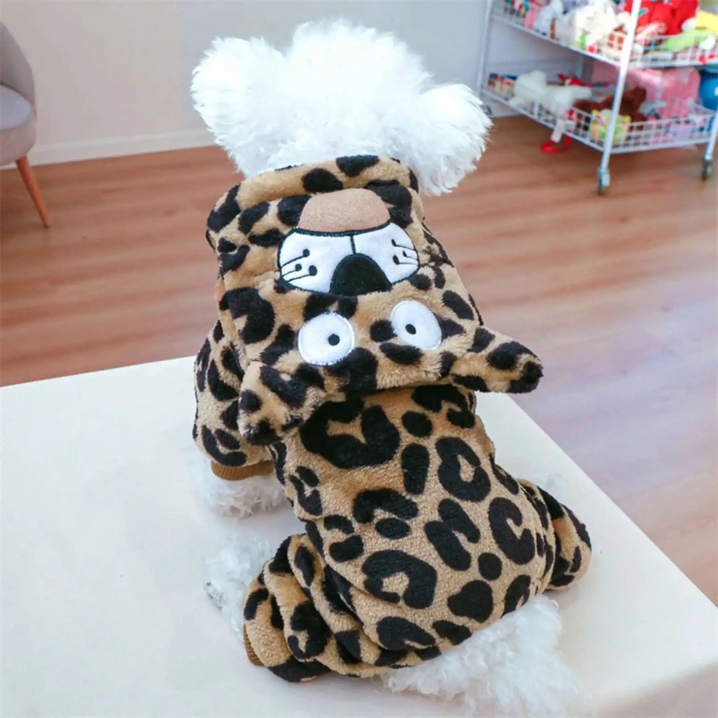 Un bichon frisé vu de dos porte un déguisement pour chien design léopard. 