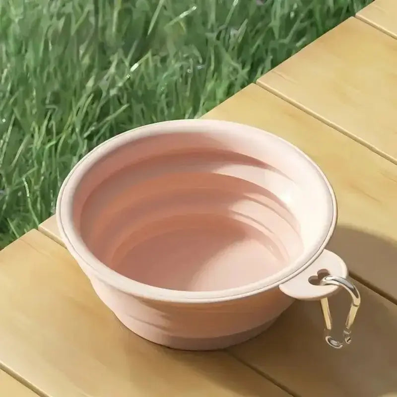 Une gamelle pour chien de couleur rose sur une table de camping.
