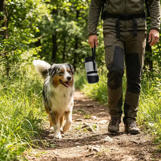 Un berger australien marche dans un sentier avec son maître avec les gourdes pour chien HydraCanis à la main.