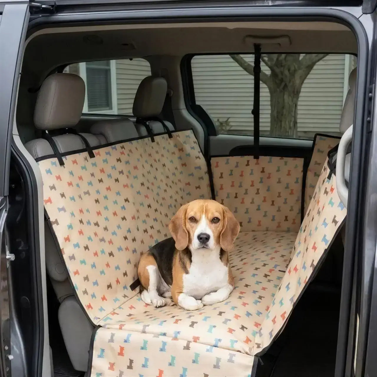 Un beagle allongé sur la housse de protection pour chien pour voiture beige avec motif de chien.
