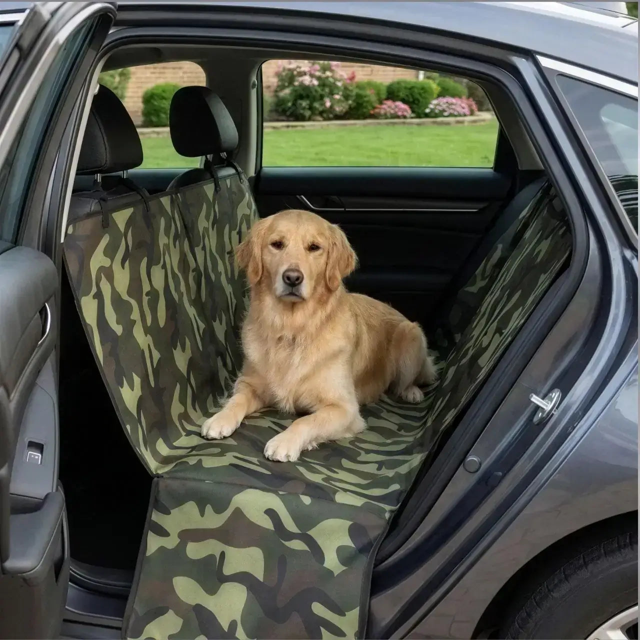 Un golden retriever allongé sur une housse de protection pour chien pour voiture vert camouflage.