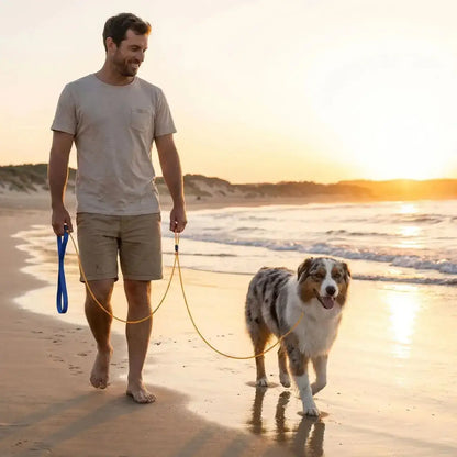 Un homme et son berger australien marchent sur la plage avec la laisse-corde pour chien.