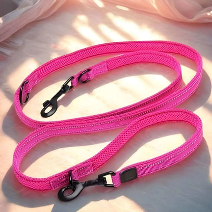 Laisse main libre pour chien au sol de couleur rose.