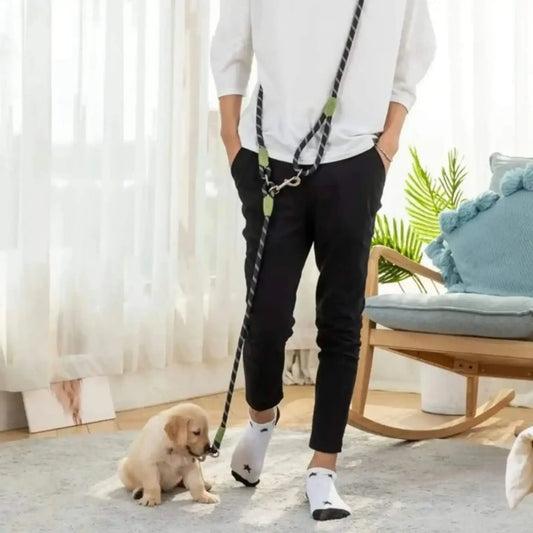 Un homme debout dans un salon avec son chiot et la laisse mains libres pour chien noire.