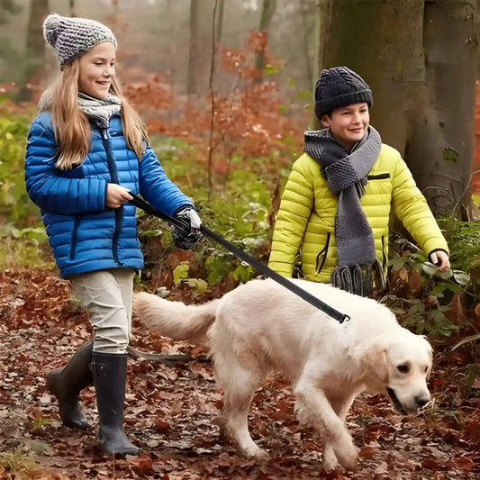 Deux enfants marchent dans la forêt avec leur golden retriever et sa laisse pour chien.