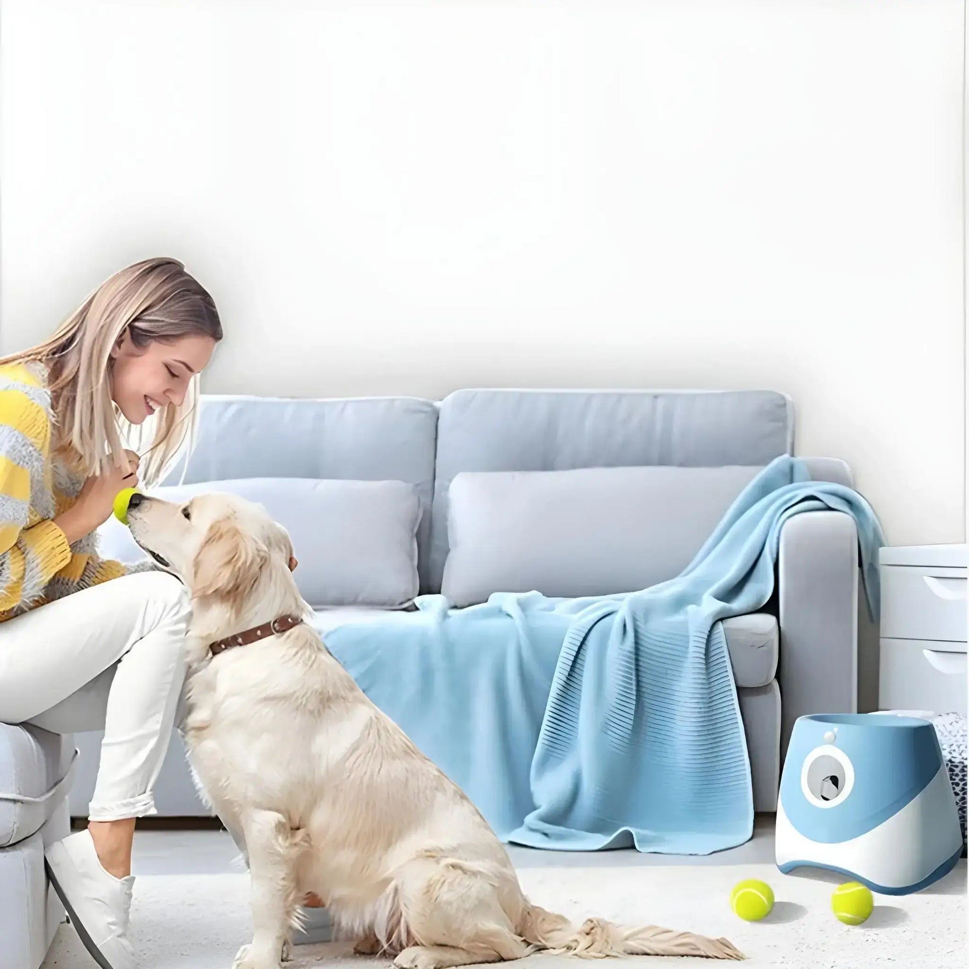 Une femme dans un salon avec son labrador et le lanceur de balle automatique bleu.