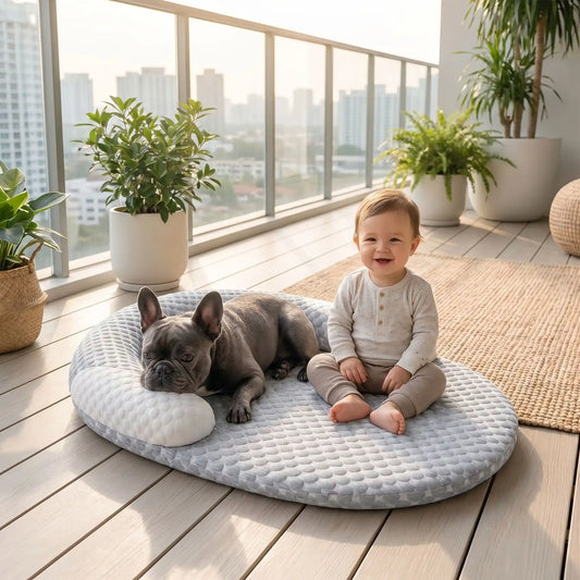Un bébé sur un balcon assis avec son bouledogue français allongé sur le matelas rafraichissant pour chien.