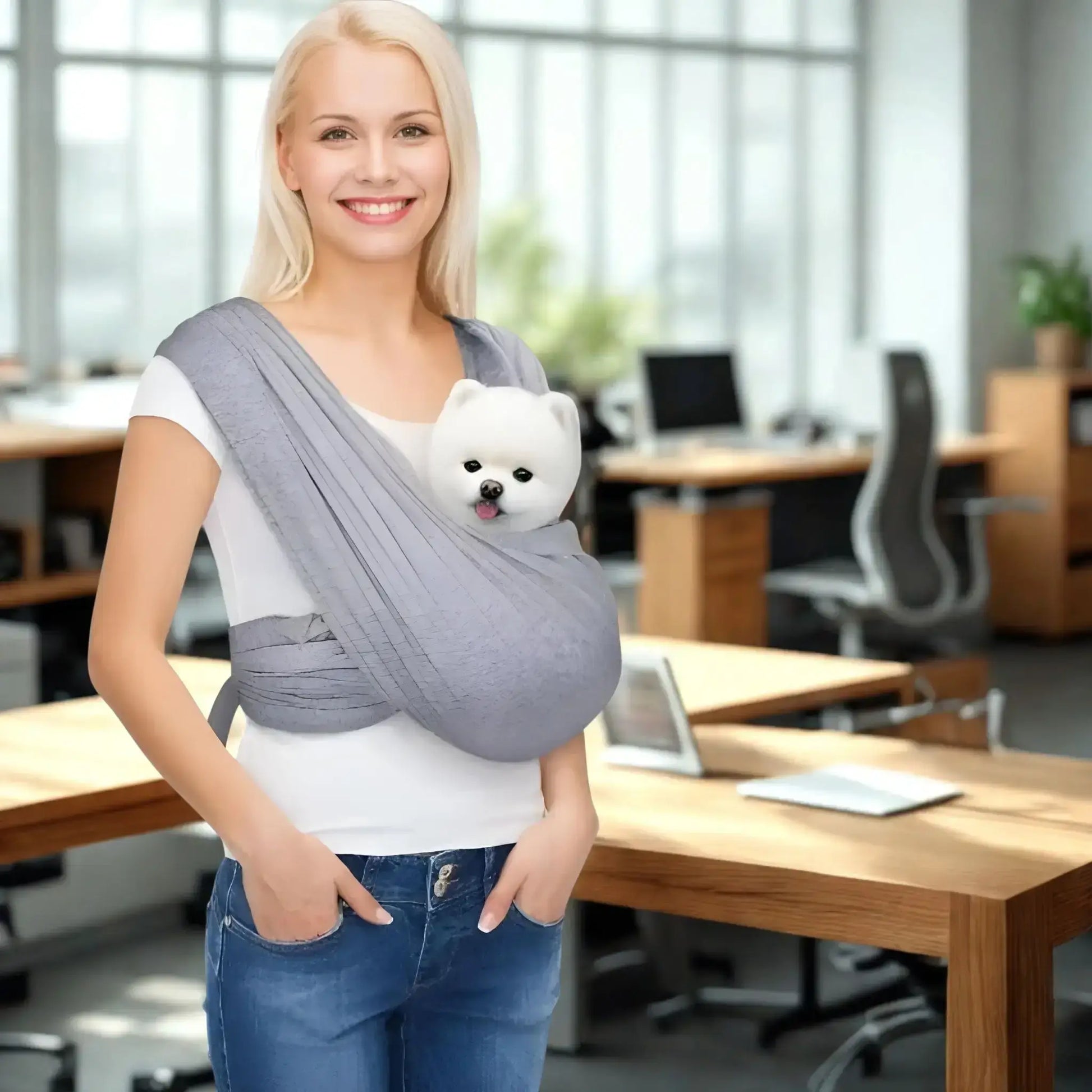 Une femme dans un bureau porte son spitz japonais nain dans son porte-chien gris.