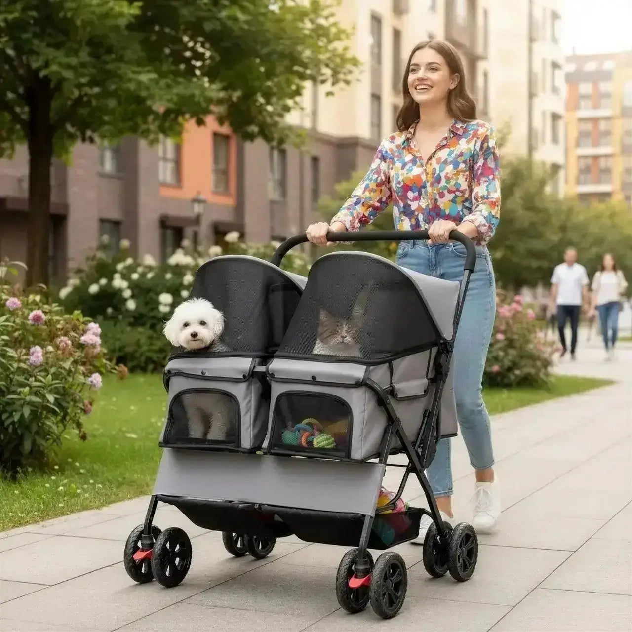Une femme sur le trottoir avec son bichon et son chat dans la poussette à chien double.