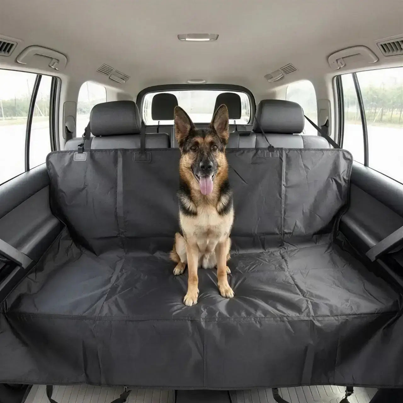 Un berger allemand assis sur le siège arrière sur la protection de siège de voiture pour chien.