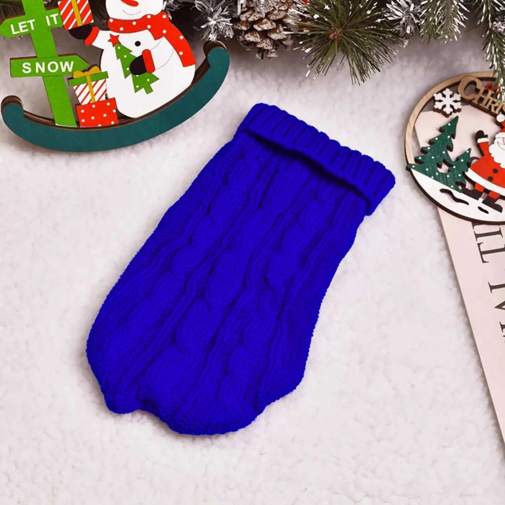 Un pull pour chien sur une table de couleur bleue.