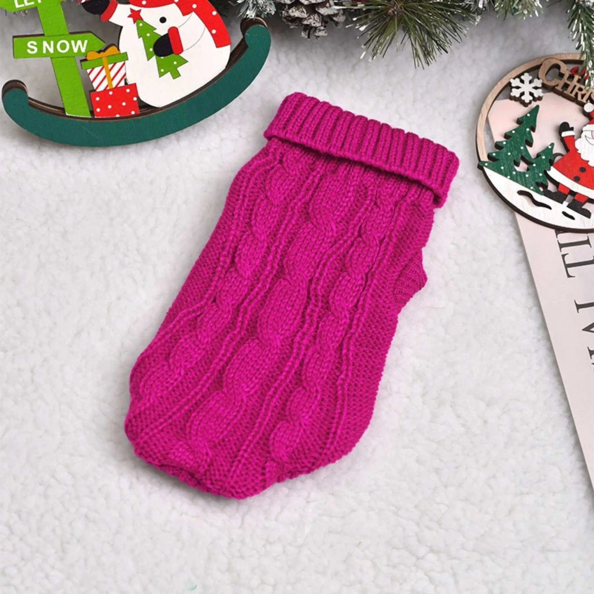 Un pull pour chien sur une table de couleur rose foncé.