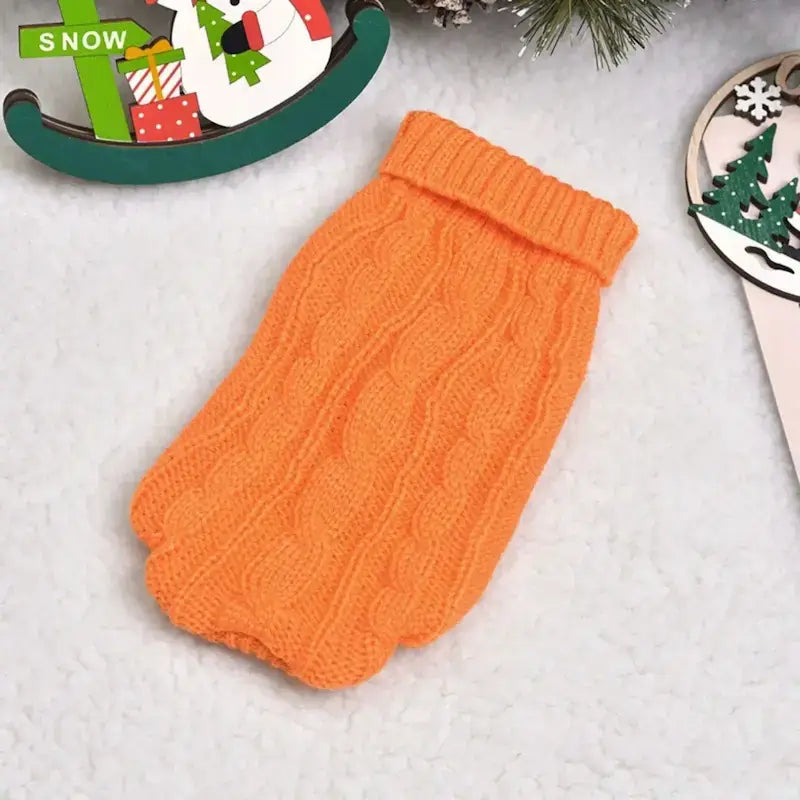 Un pull pour chien sur une table de couleur orange.