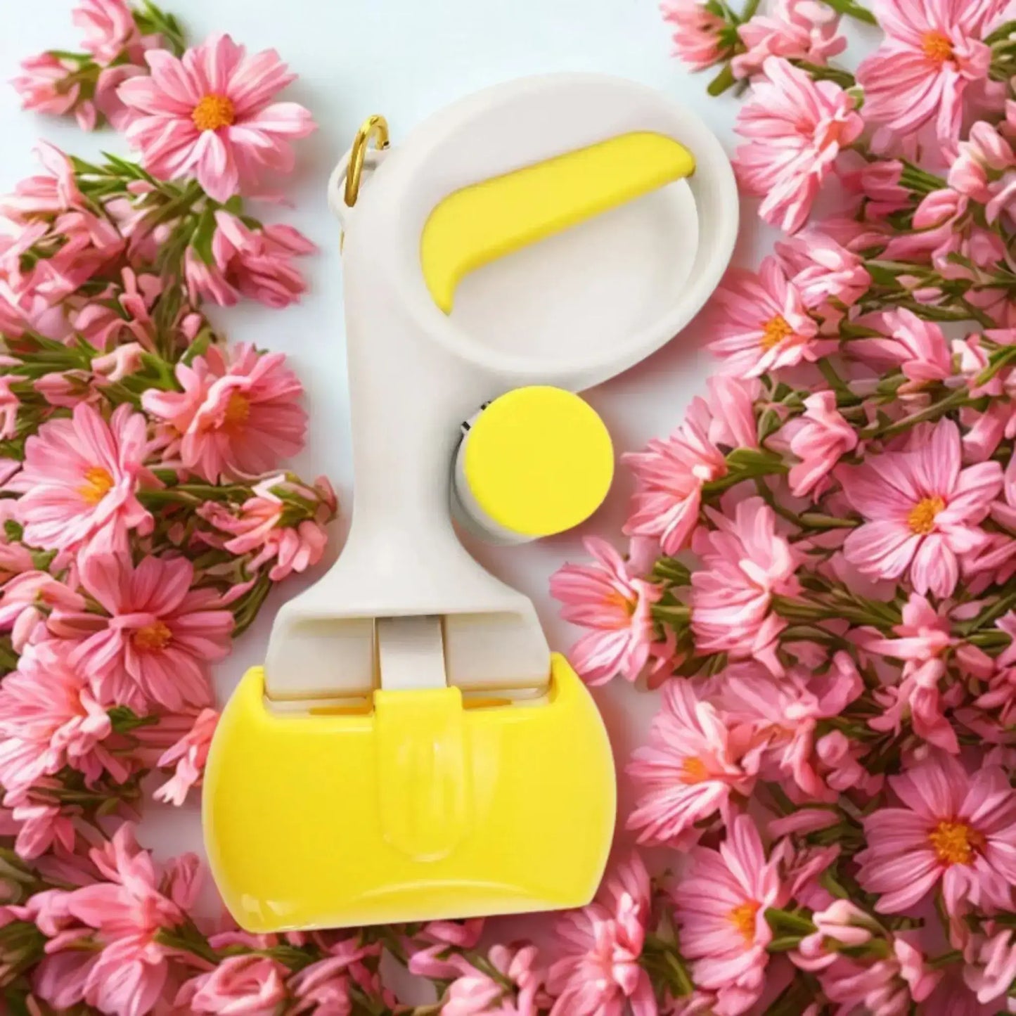 Un ramasse-crottes pour chien de couleur jaune avec des fleurs roses.