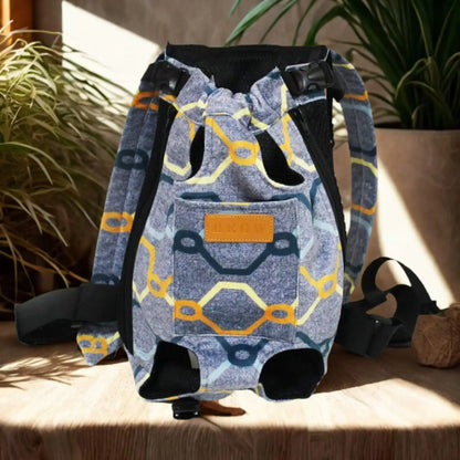 Un sac à dos pour chien porté par l'humain de couleur bleu avec rayures colorées sur une table avec plante à côté.
