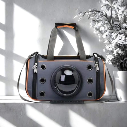 Un sac à dos pour chien de couleur gris et orange sur un rebord mural avec un vase de fleurs blanches à côté.