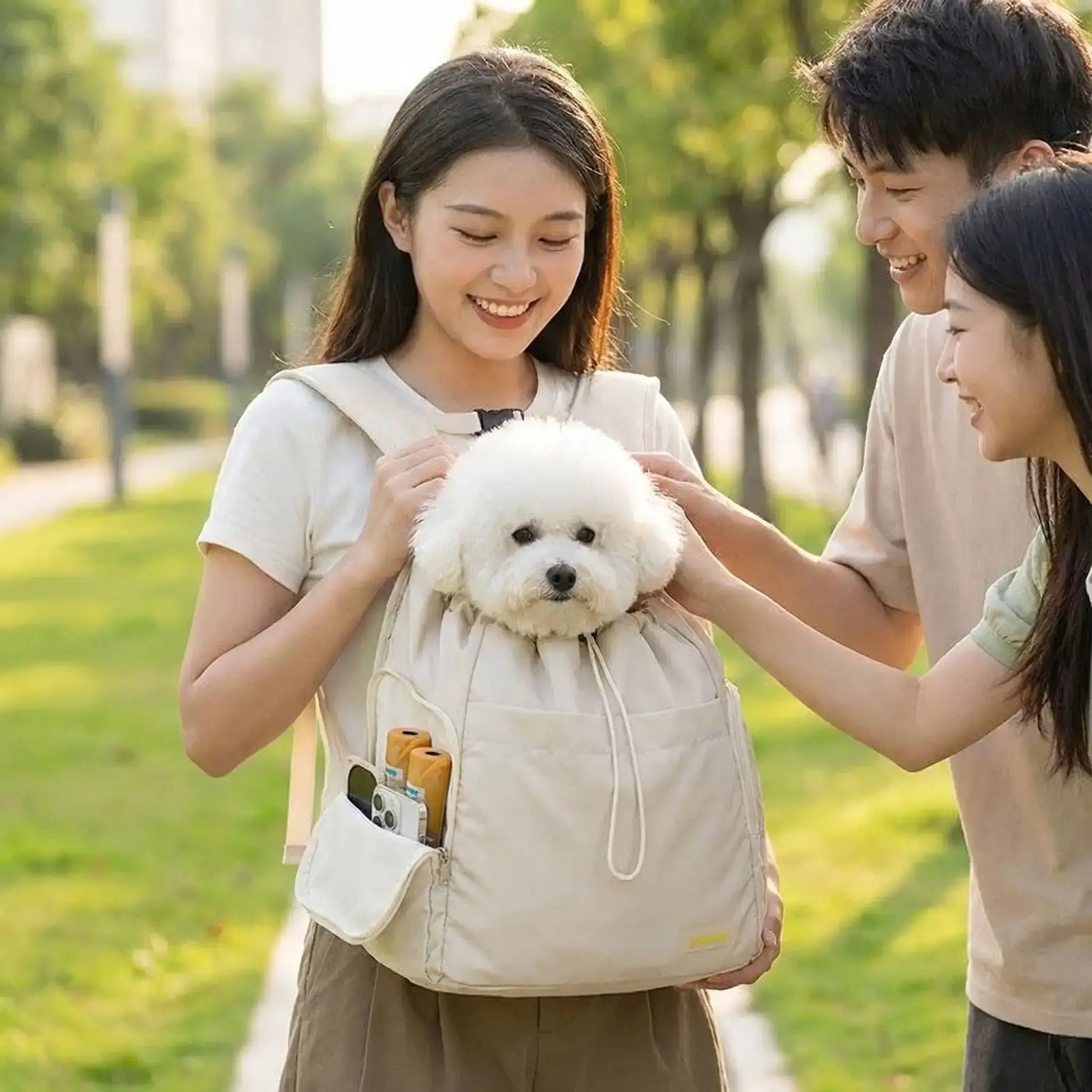 Une femme avec ses amies qui caresse son bichon frisé dans le sac à dos pour chien de randonnée.