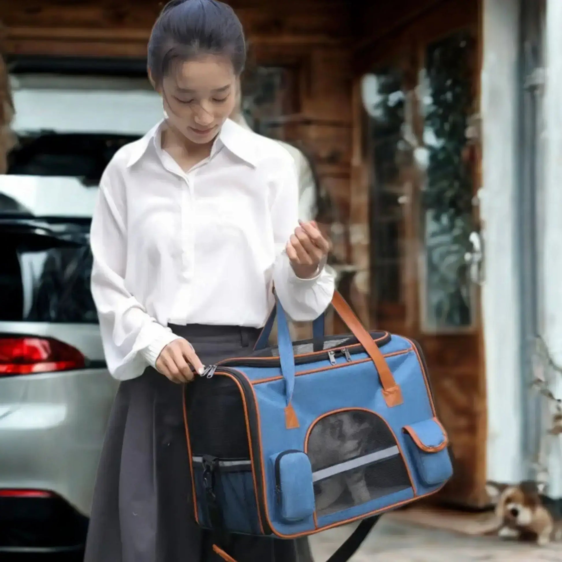 Une femme dans son stationnement porte un sac de transport pour chien bleu sous le bras.