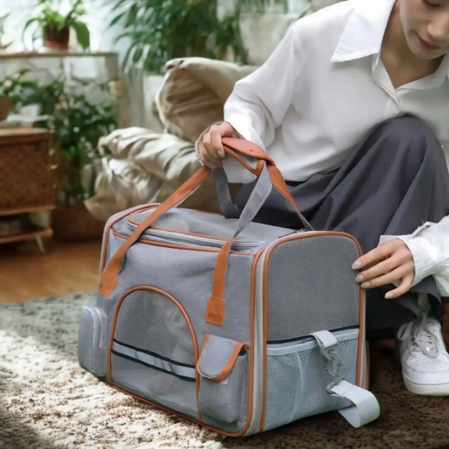 Une femme dans un salon avec son sac de transport pour chien gris.