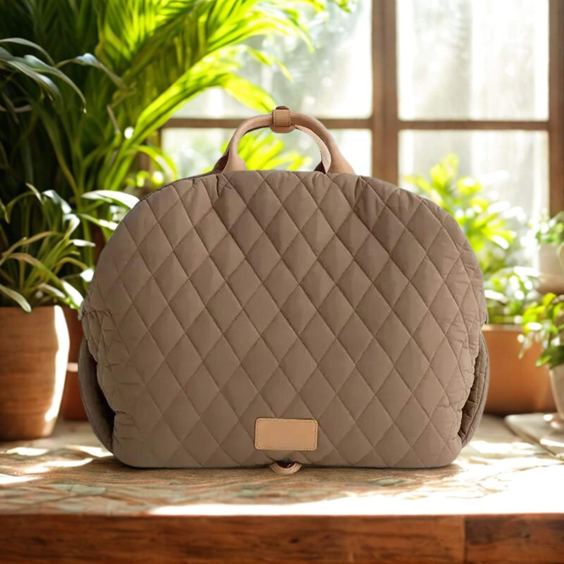 Sac de transport pour chien de couleur kaki sur un comptoir avec des plantes vertes derrière