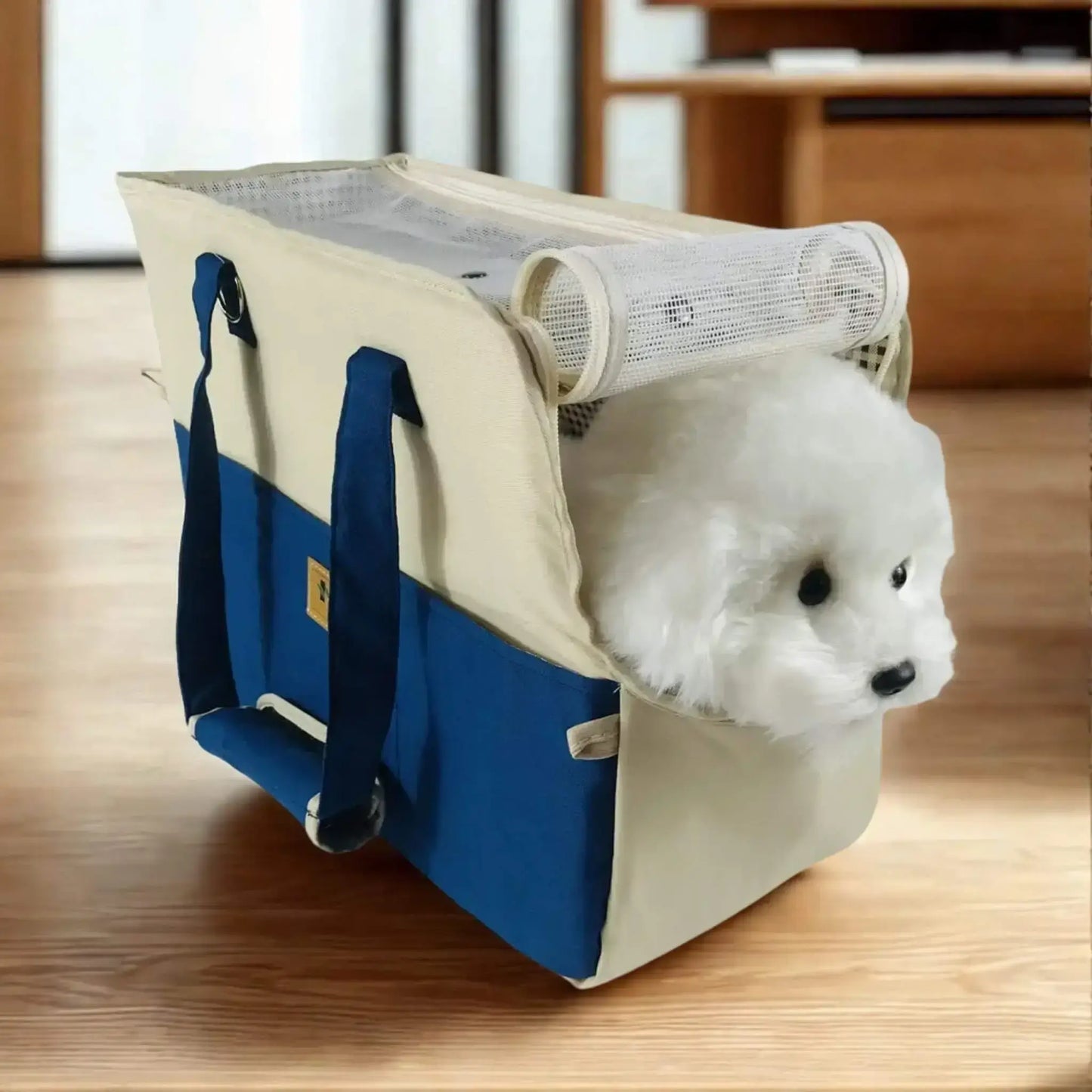 Un sac pour transporter un chien bleu sur une table avec un bichon frisé à l'intérieur.