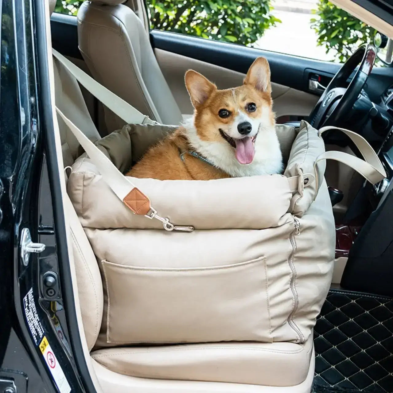 Un corgi assis dans son siège d'auto pour chien beige sur le siège avant de la voiture.