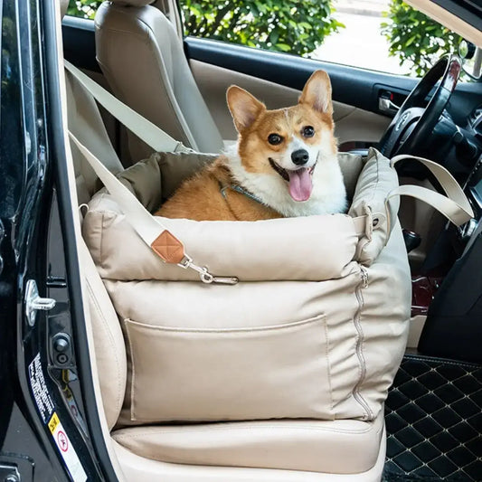 Un corgi assis dans son siège d'auto pour chien beige sur le siège avant de la voiture.