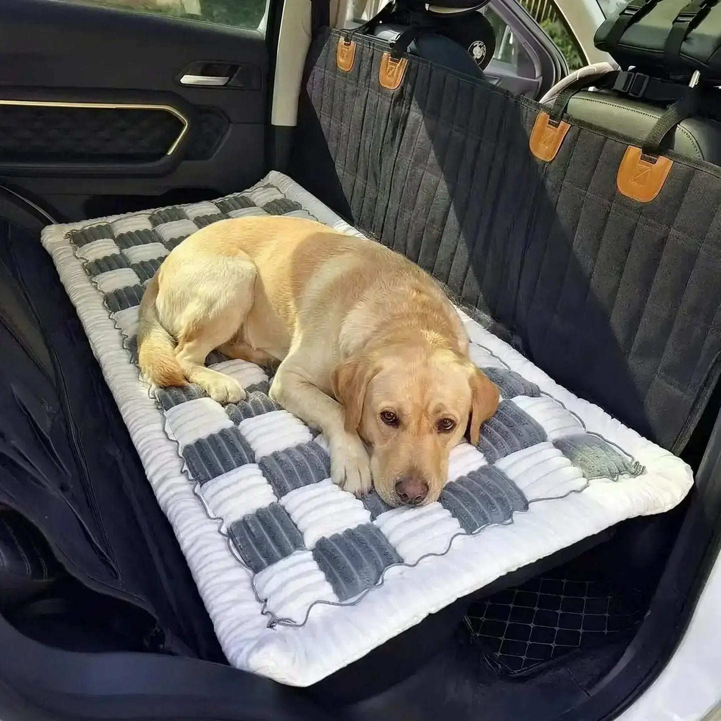 Un labrador allongé sur un tapis pour chien de voiture bleu sur le siège arrière