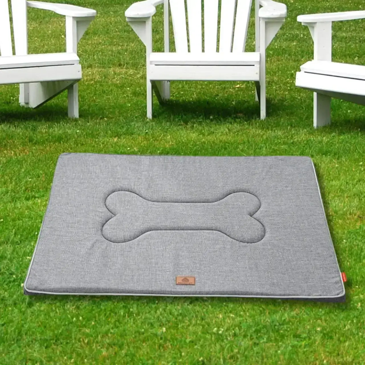 Un tapis imperméable pour chien gris pâle sur une pelouse avec des chaises de terrasse.